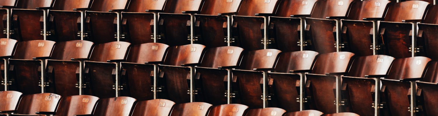 Rows of brown wooden seats in a lecture hall